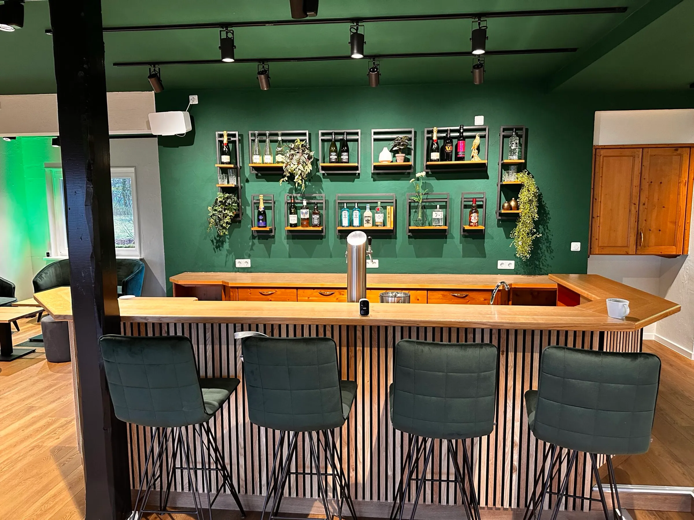 Stilvolle Bar mit grüner Wand und Holztheke